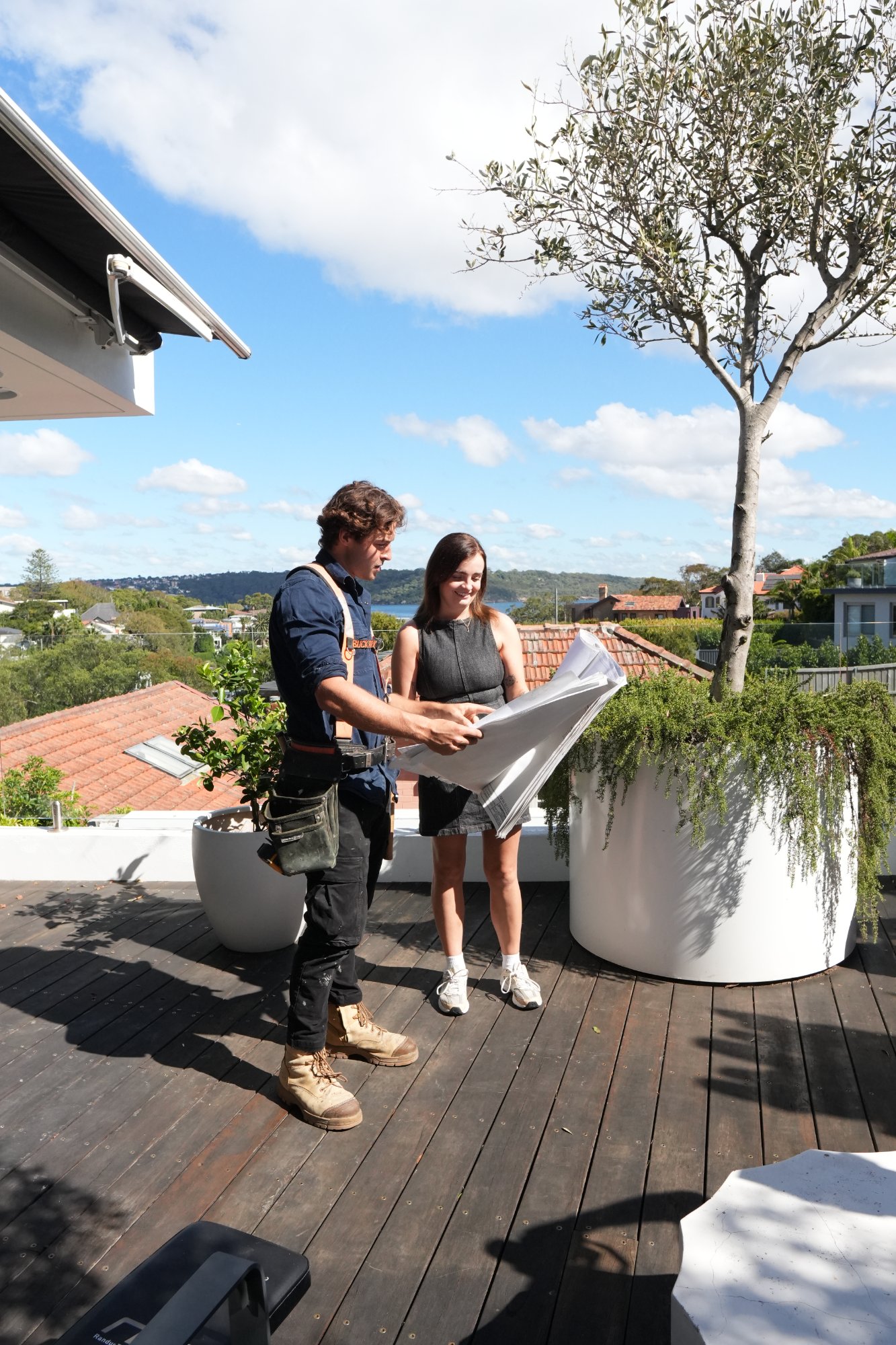 Muster site supervisor reviewing job plans with a client on an Australian construction site