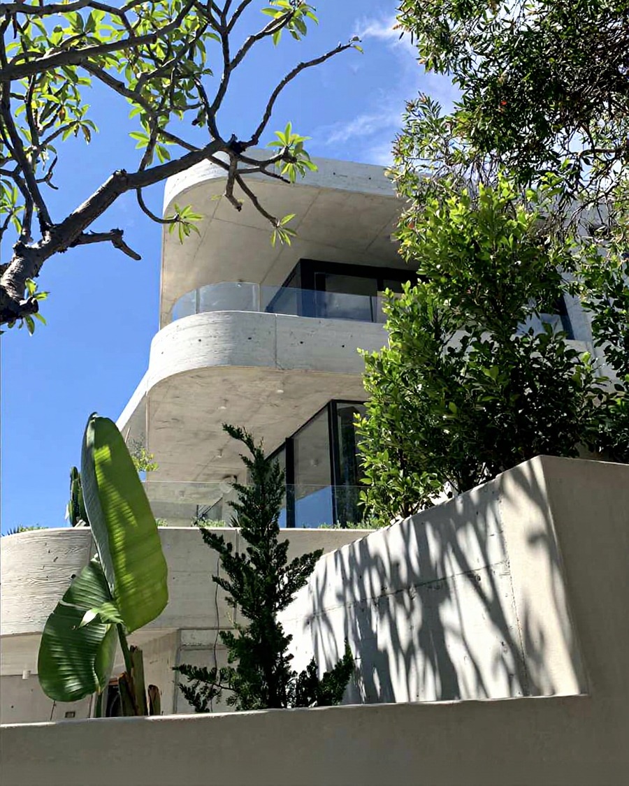 Curved concrete street facade with banana plant and surrounding trees, Auld family build