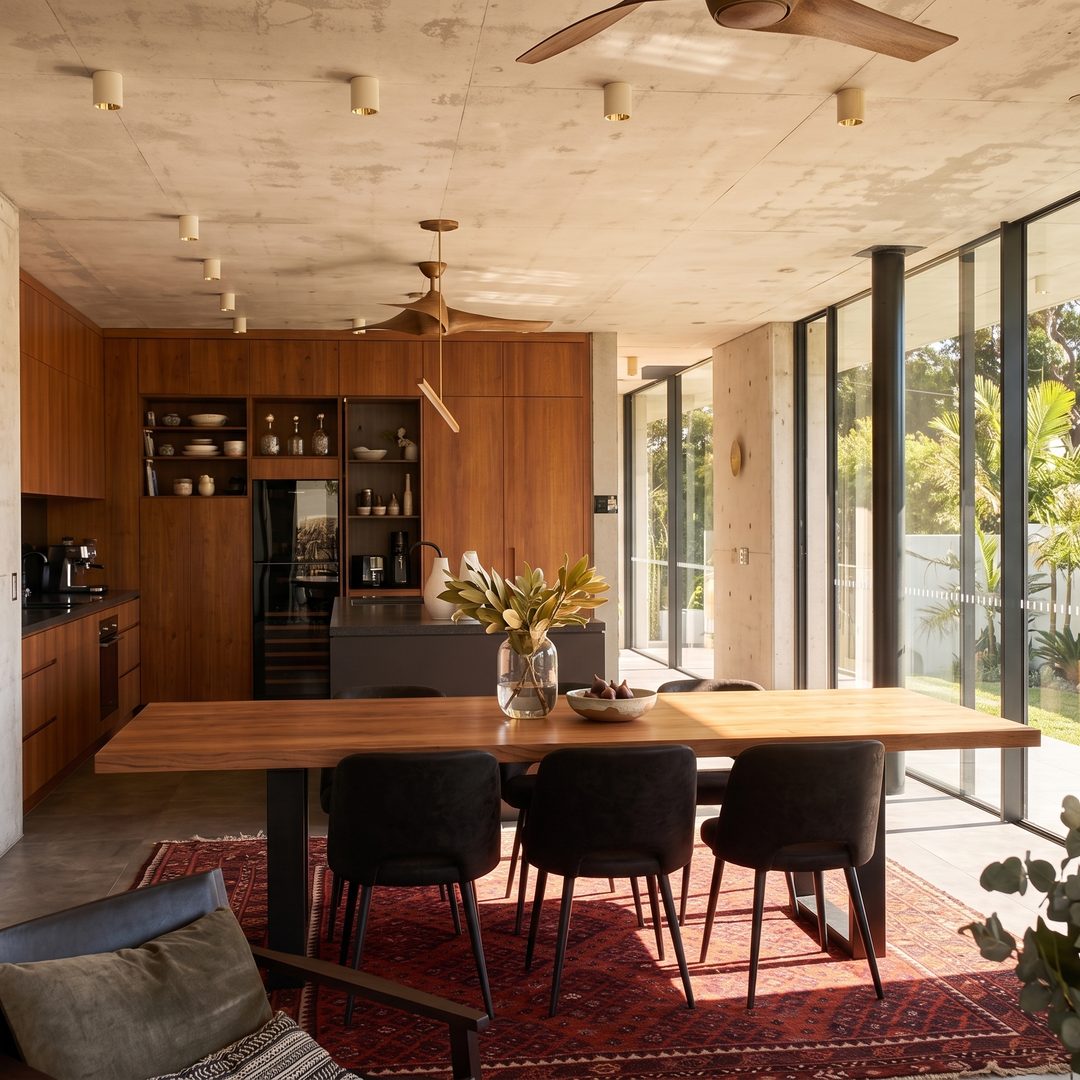 Board-formed concrete kitchen and dining with timber joinery, open to a Sydney garden